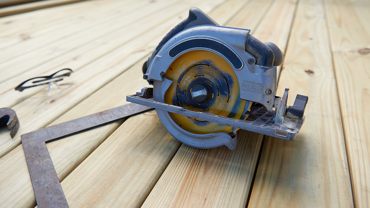 Circular saw, ruler and safety glasses sitting on a deck made of KDAT lumber