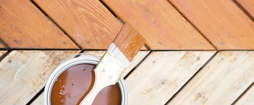 Pressure-Treated Deck Boards Being Stained with Paint Brush